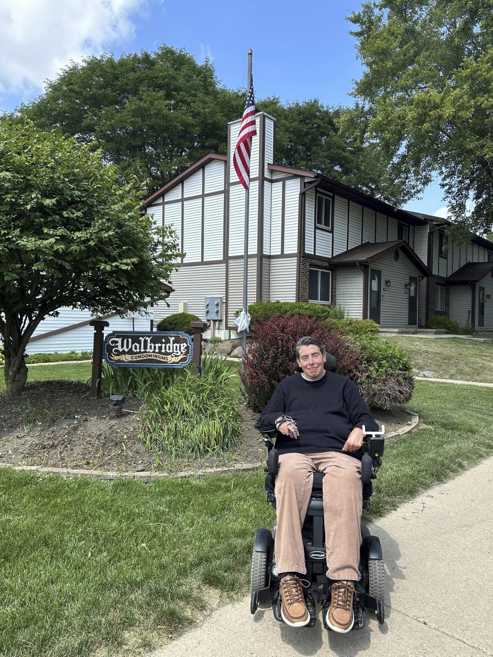 Wisconsin state Rep. Jimmy Anderson poses, Thursday, Aug. 10, 2023, in Madison, Wis., outside of a condominium complex that is disconnected from the rest of his legislative district. A lawsuit contends that such disconnected sections of land violate the state constitution and that the current districts should be redrawn before the 2024 election. (AP Photo/Scott Bauer)