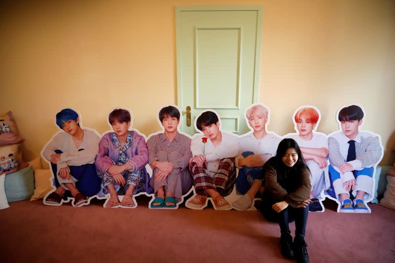 A fan of K-pop idol boy band BTS poses for photographs with cut-out of BTS at a pop-up store selling BTS goods in Seoul