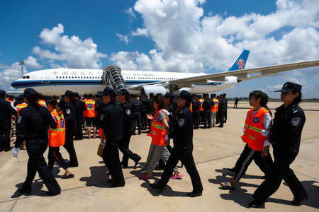 Chinese nationals (in orange vests) who were arrested over a suspected internet scam, are escorted by Chinese police officers before they were deported at Phnom Penh International Airport, in Phnom Penh, Cambodia, October 12, 2017. REUTERS/Samrang Pring