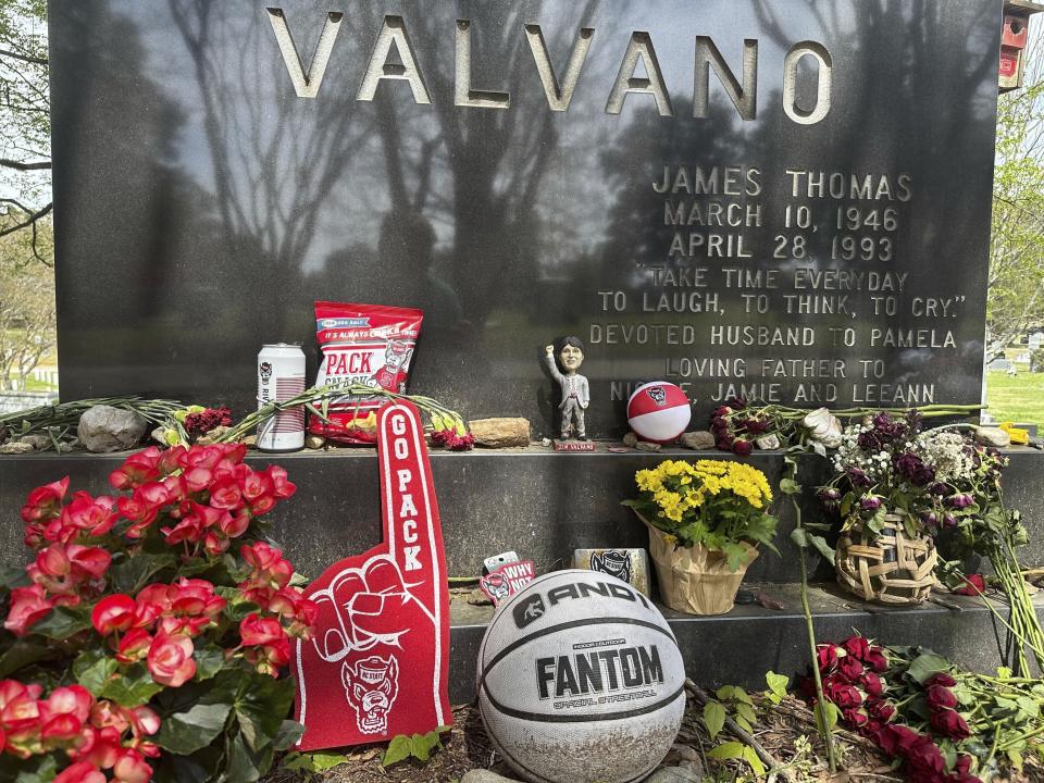 The grave of charismatic North Carolina State men’s basketball coach Jim Valvano, adorned with flowers and numerous Wolfpack-related tributes, is shown at Oakwood Cemetery in Raleigh, N.C., Monday, April 1, 2024. N.C. State’s men’s basketball team is in the Final Four for the first time since 1983, while the Wolfpack women are in the Final Four for the first time since 1998. (AP Photo/Aaron Beard)