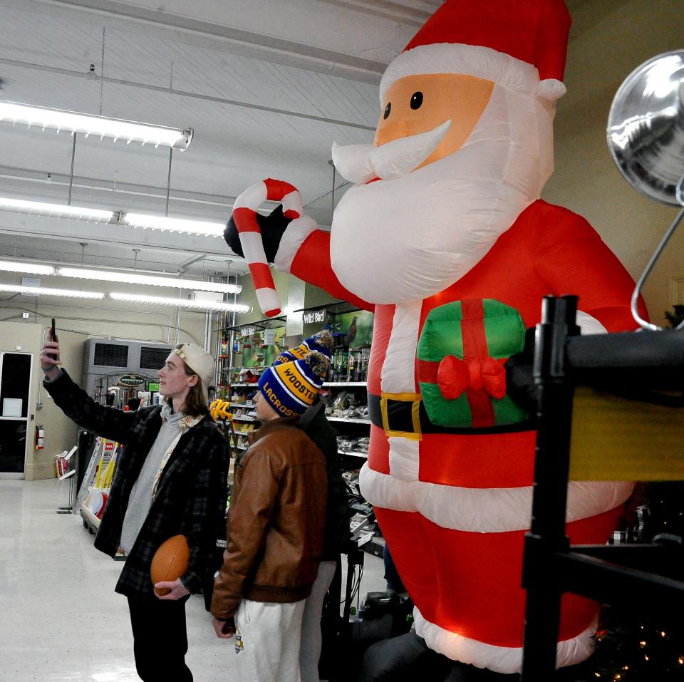 Talon Keys, Liam Ozar and Brook Laughlin take a selfie with an inflatable Santa in a hardware store on the square in Wooster Friday during Window Wonderland.