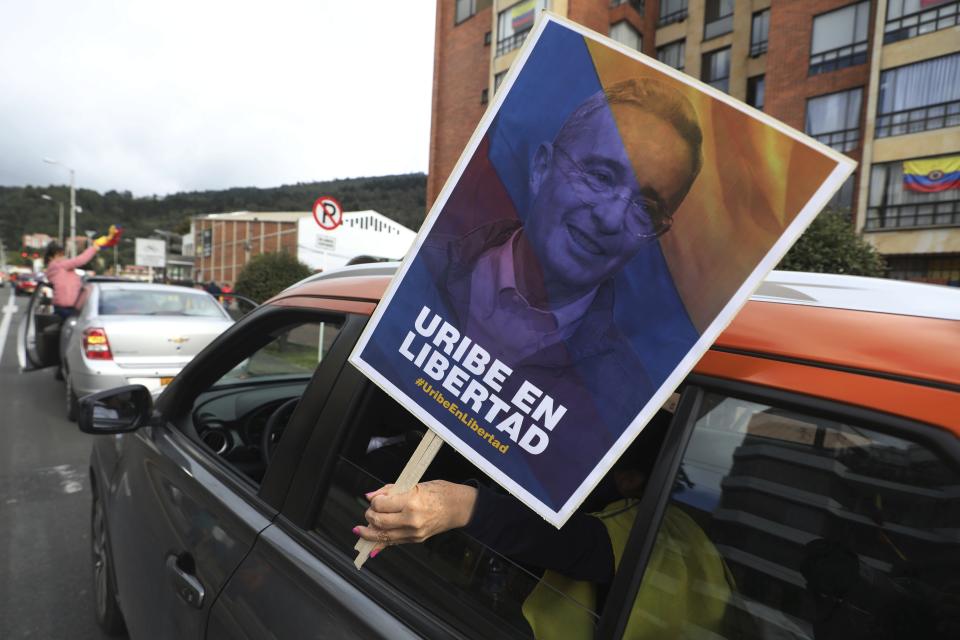 A supporter of former President Alvaro Uribe holding a banner with an image of him with a message that reads in Spanish: "Free Uribe", takes part in caravan to protest the Supreme Court decision to place Uribe under house arrest while it advances a witness tampering investigation against him, in Bogota, Colombia, Friday, Aug. 7, 2020. (AP Photo/Fernando Vergara)