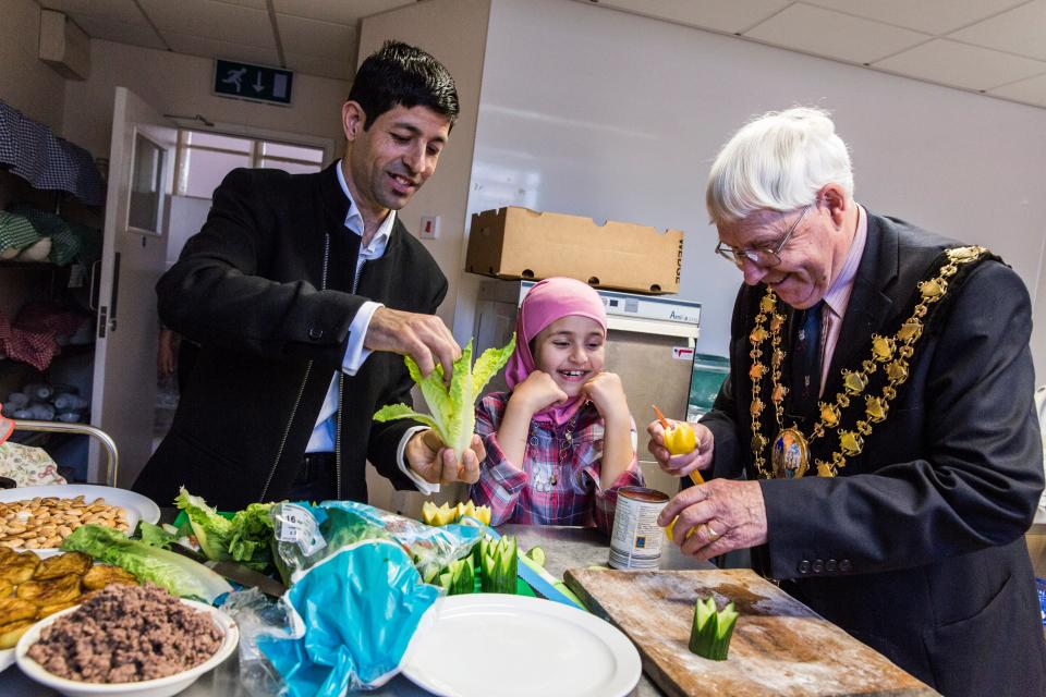 <p>Muhaned Alchik and his daughter Sara, 8, help Mayor John Adams-Lewis to prepare Syrian food, at a church hall in Cardigan, Wales</p>Andrew McConnel