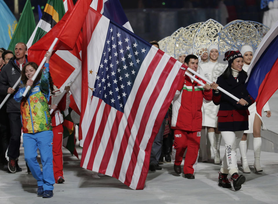 United States' Julie Chu, right, carries her nation's flag while participating in the closing ceremony of the 2014 Winter Olympics, Sunday, Feb. 23, 2014, in Sochi, Russia. (AP Photo/Charlie Riedel)