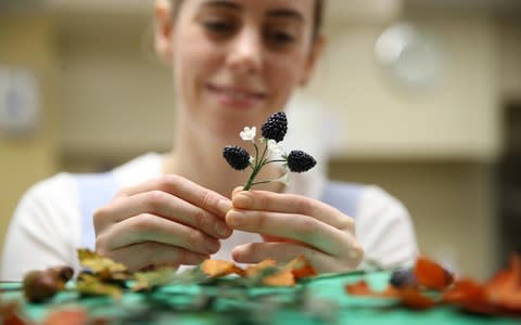 Baker Sophie Cabot puts the finishing touches to the cake decorations - Credit: Reuters