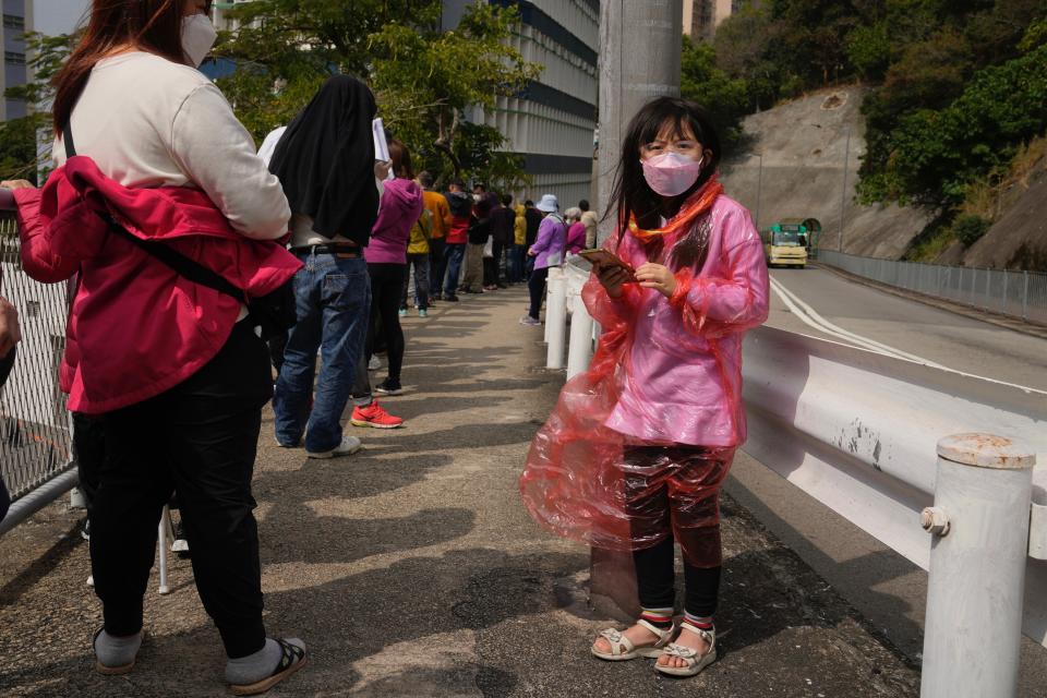 Residents line up to get tested for the coronavirus at a temporary testing center for COVID-19, in Hong Kong, Tuesday, Feb. 15, 2022. Hong Kong's leader on Tuesday said a surge of coronavirus cases is overwhelming the city's emergency resources, but defended strict measures that have been imposed. (AP Photo/Kin Cheung)