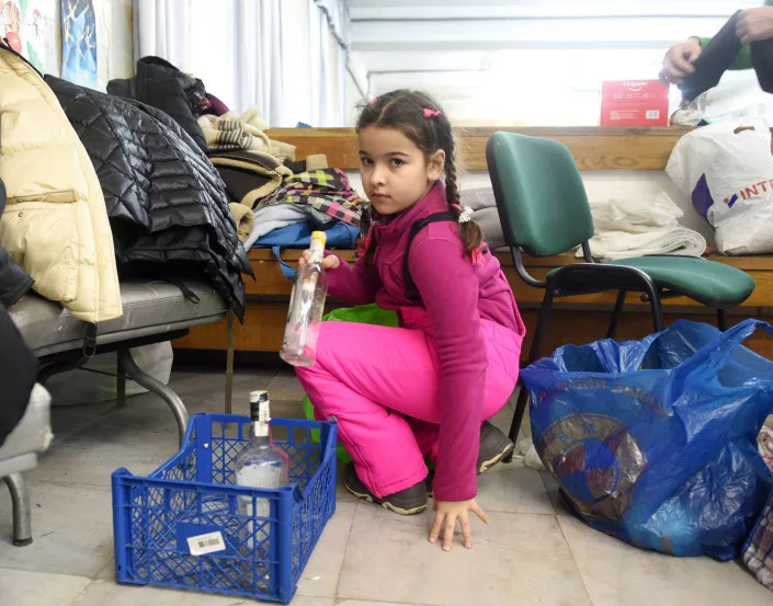 A small girl sorts empty bottles.