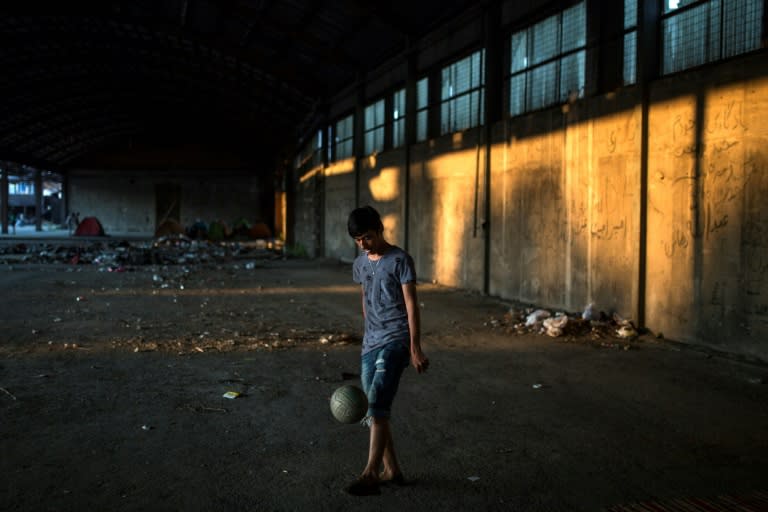 An Afghan migrant plays with a ball at an abandoned factory which has been his temporary home in Patras, southwestern Greece