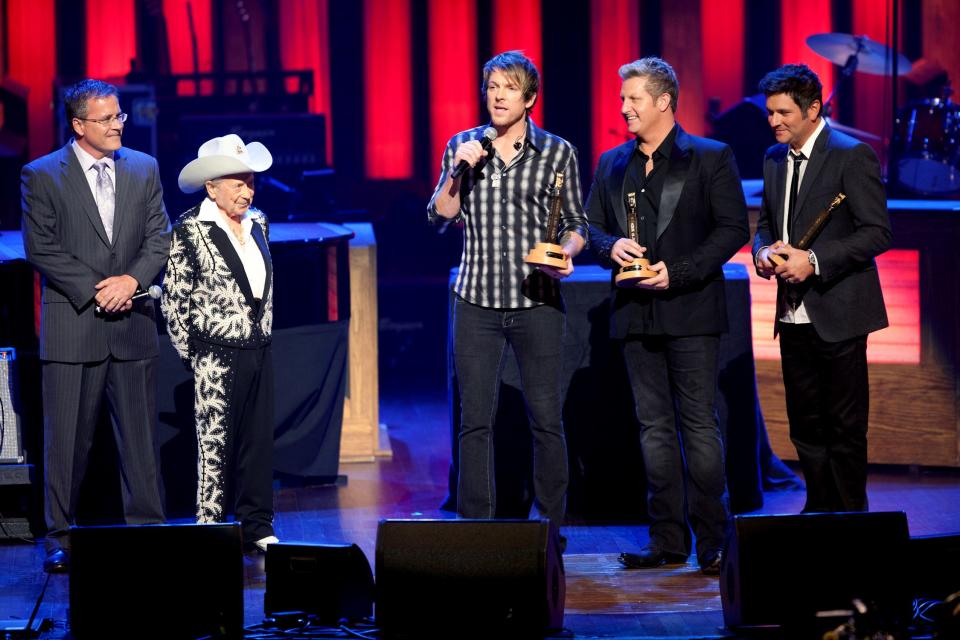 Opry General Manager Pete Fisher, left, and Little Jimmy Dickens look on as Joe Don Rooney says a few words after he and fellow Rascal Flatts members Gary LeVox and Jay DeMarcus received their induction honors as the newest members of the Grand Ole Opry on Oct. 8, 2011.