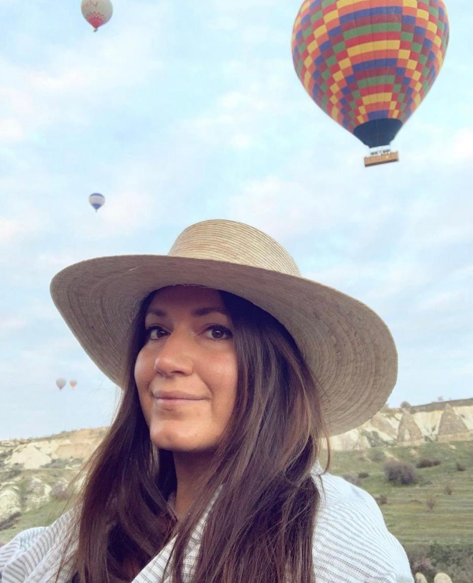 A woman wearing a hat in front of hot air balloons.
