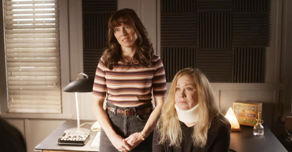 Linda standing and Christina sitting in front of a desk