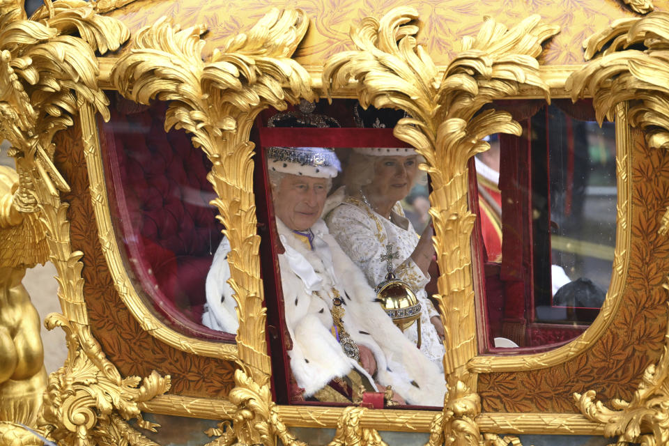 El rey Carlos III saluda a bordo de un carruaje dorado en su camino de regreso al Palacio de Buckingham desde la Abadía de Westminster tras su ceremonia de coronación, en Londres, el sábado 6 de mayo de 2023. (Sebastien Bozon/Pool via AP)