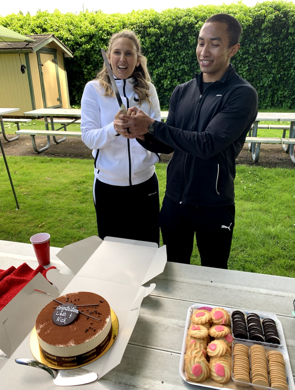 Bosello and Smith wear their wedding tracksuits as they prepare to cut their cake.