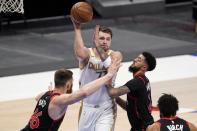 Toronto Raptors' Aron Baynes (46), Jalen Harris (2) and Khem Birch, bottom right, defend as Dallas Mavericks guard Luka Doncic (77) makes a pass in the first half of an NBA basketball game in Dallas, Friday, May 14, 2021. (AP Photo/Tony Gutierrez)