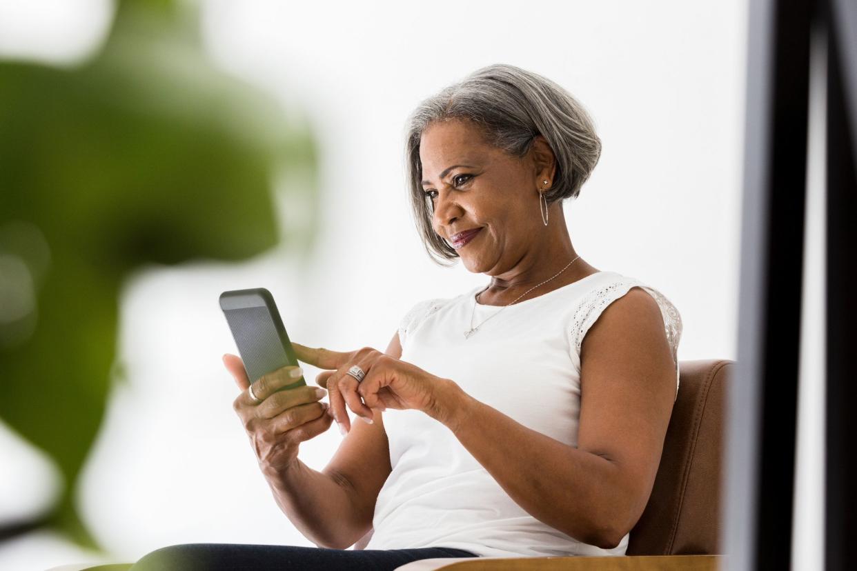 Attractive senior African American woman smiles while video chatting with her grandchildren.