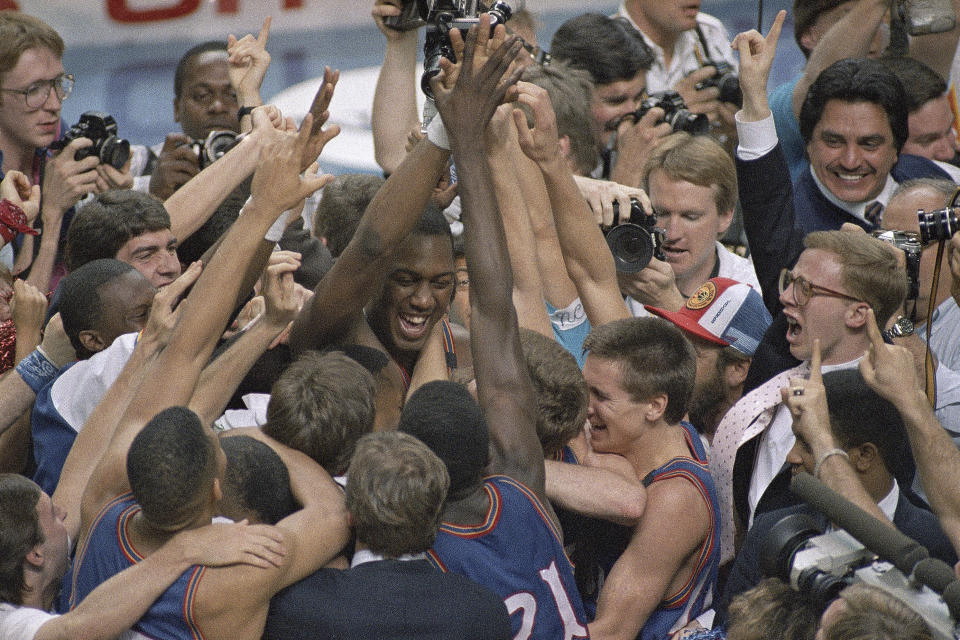 FILE - Kansas' Danny Manning, facing camera left of center, is mobbed by fans and teammates after he led his team to an 83-79 victory over Oklahoma in the championship game of the Final Four NCAA college basketball tournament in Kansas City, Mo., Monday, April 4, 1988. (AP Photo/Susan Ragan, File)