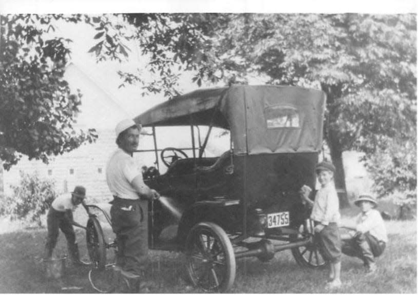 Cleaning the family’s Model T, are brother John, from left, father Wilbur, Kenneth, and brother Loren Nichols in front of the Nichols family home, 3936 Rocky River Drive, West Park, Ohio.