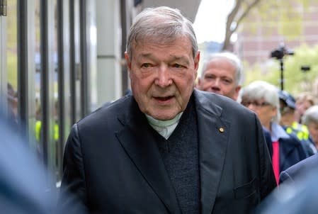 FILE PHOTO - Vatican Treasurer Cardinal George Pell is surrounded by Australian police as he leaves the Melbourne Magistrates Court in Australia