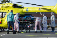 A COVID-19 patient is being carried into a helicopter at Flevoziekenhuis, or FlevoHospital, in Almere, Netherlands, Friday, Oct. 23, 2020. In the latest sign of the scale of the coronavirus pandemic sweeping across Europe, a helicopter is scheduled to start airlifting COVID-19 patients from the Netherlands to an intensive care unit in the German city of Muenster.(AP Photo/Peter Dejong)