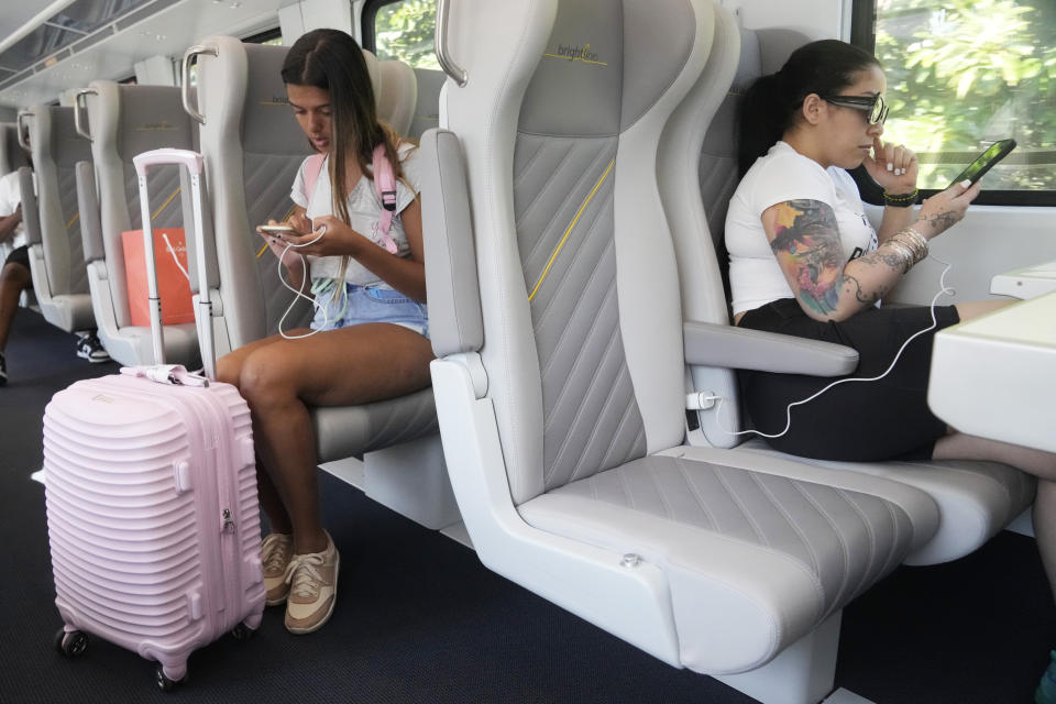 Brightline passengers look at their phones, Friday, Sept. 8, 2023, in Aventura, Fla. Brightline is launching a new route from Miami to Orlando on Friday, Sept. 22. (AP Photo/Marta Lavandier)