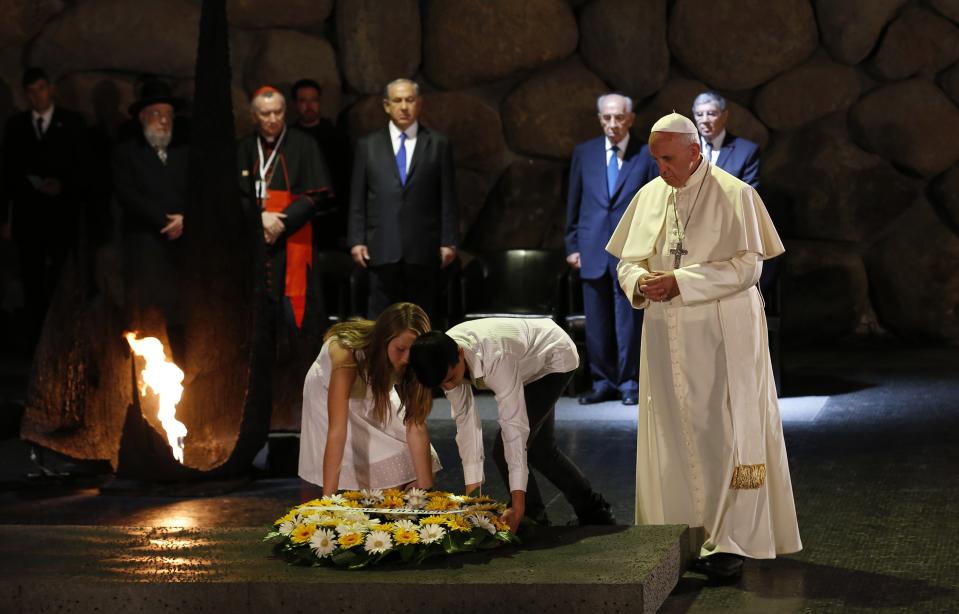 Pope Francis stands next to two young students as they lay a wreath during a ceremony at the Yad Vashem Holocaust memorial in Jerusalem