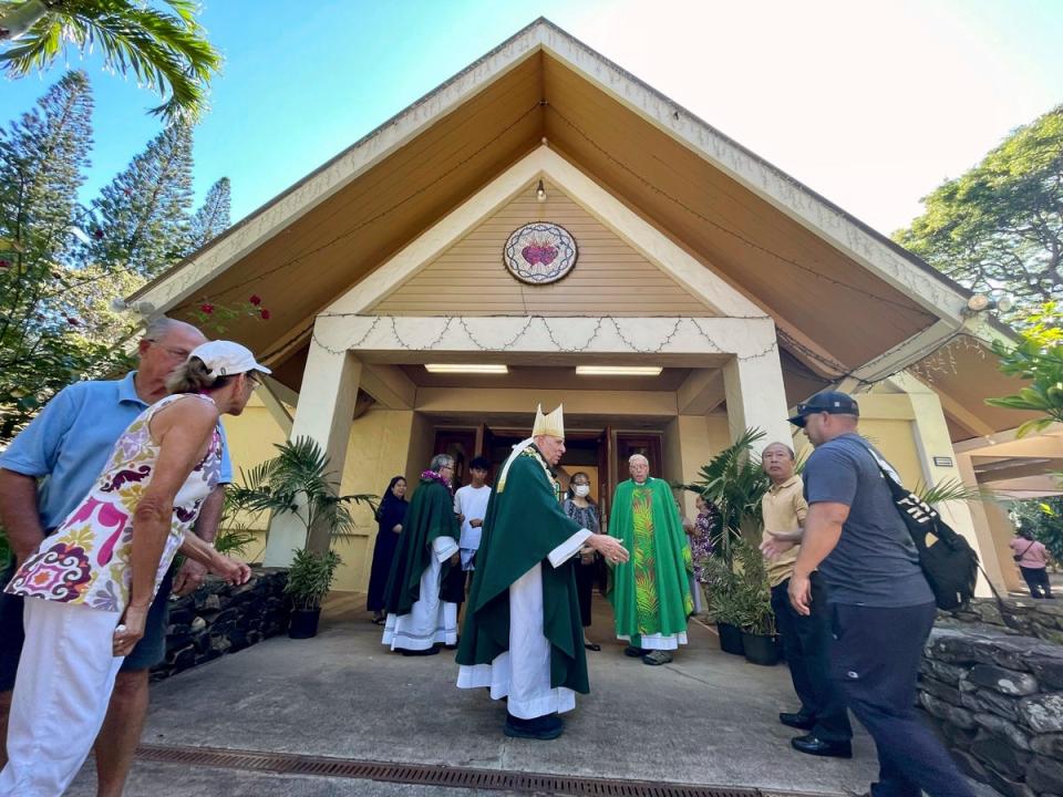 Most Rev. Clarence “Larry” Silva, the Bishop of Honolulu, greets parishioners after Mass at Sacred Hearts Mission Church on Sunday, after it was spared by wildfires (Associated Press)