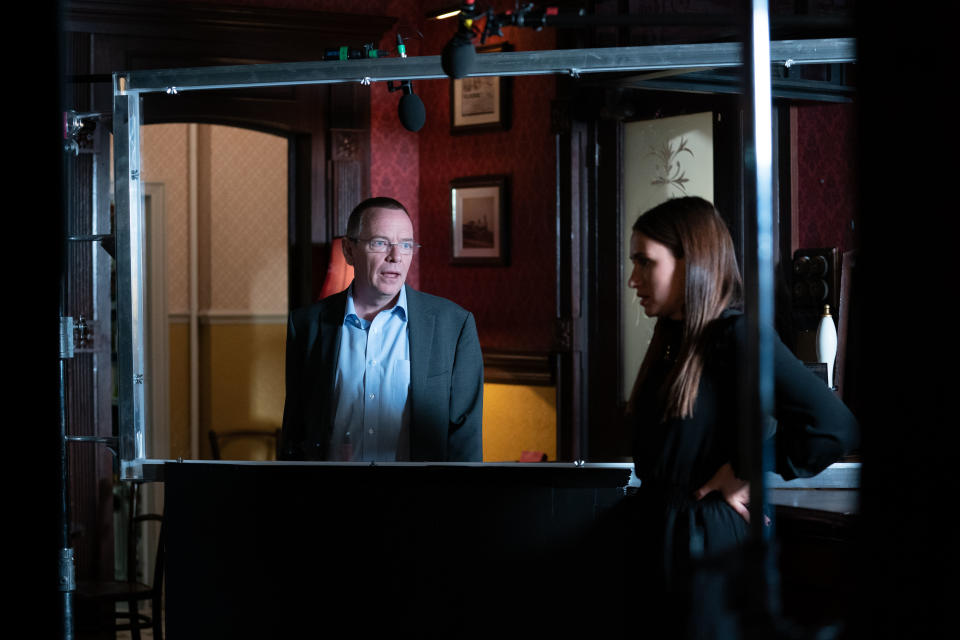 Adam Woodyatt and Milly Zero filming on the 'EastEnders' set separated by a Perspex screen. (BBC) 