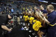 Michigan cheerleaders pose for the TV camera before a third-round game of the NCAA college basketball tournament between the Michigan and the Texas Saturday, March 22, 2014, in Milwaukee. (AP Photo/Jeffrey Phelps)
