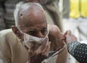 An elderly receives Covid-19 vaccination at a makeshift center in a government school in New Delhi, India, Friday, Jan. 28, 2022. Indian health officials said that the first signs of COVID-19 infections plateauing in some parts of the vast country were being seen, but cautioned that cases were still surging in some states. (AP Photo/Manish Swarup)