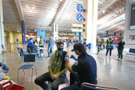 FILE - In this May 2, 2021, file photo, Austin Kennedy, left, a Seattle Sounders season ticket holder, gets the Johnson & Johnson COVID-19 vaccine at a clinic in a concourse at Lumen Field prior to an MLS soccer match between the Sounders and the Los Angeles Galaxy. States across the country are dramatically scaling back their COVID-19 vaccine orders as interest in the shots wanes, putting the goal of herd immunity further out of reach. (AP Photo/Ted S. Warren, File)