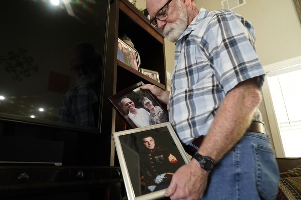 Joey Reed holds photos of his son Marine veteran and Russian prisoner Trevor Reed at his home in Fort Worth, Texas, Tuesday, Feb. 15, 2022. Russia is holding Trevor Reed, who was sentenced to nine years on charges he assaulted a police officer. (AP Photo/LM Otero)