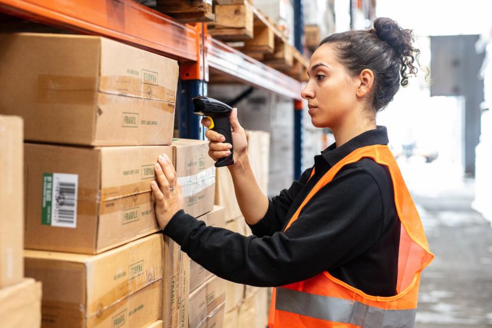 A woman scanning boxes in a warehouse