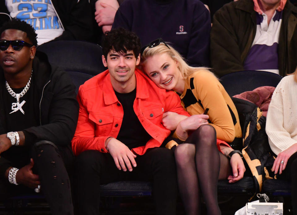 Joe Jonas smiling and Sophie Turner cuddling up to him at a basketball game