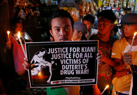 Protesters and residents hold lighted candles and placards at the wake of Kian Loyd delos Santos, a 17-year-old high school student, who was among the people shot dead last week in an escalation of President Rodrigo Duterte's war on drugs in Caloocan city, Metro Manila, Philippines August 25, 2017. REUTERS/Dondi Tawatao