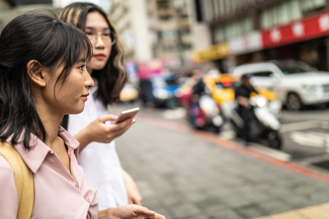 Women walking down city streets and using smartphones. (PHOTO: Getty)