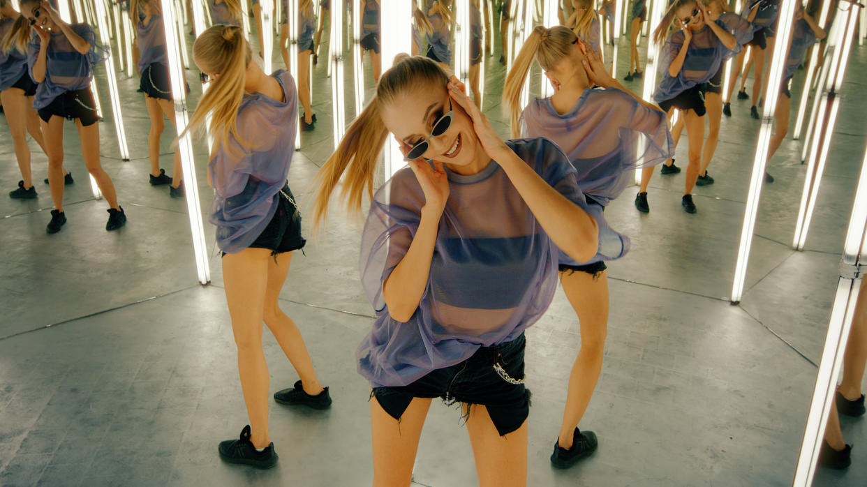  A photograph of a woman dancing in a hall of mirrors with many reflections behind her. 