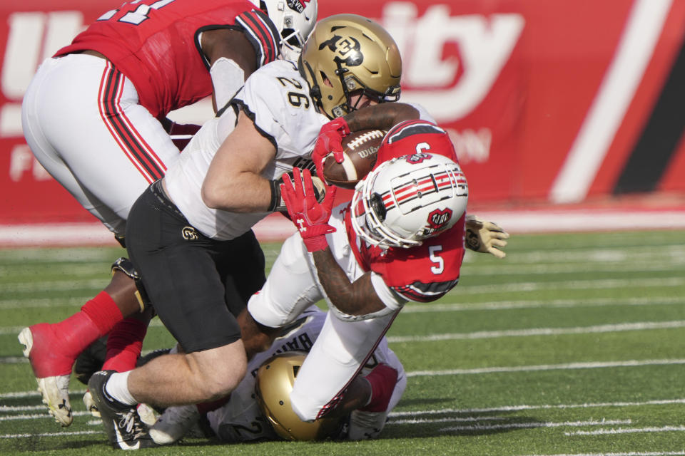 Utah running back TJ Pledger (5) is tackled by Colorado linebackers Carson Wells (26) and Robert Barnes (20) in the first half of an NCAA college football game Friday, Nov. 26, 2021, in Salt Lake City. (AP Photo/George Frey)