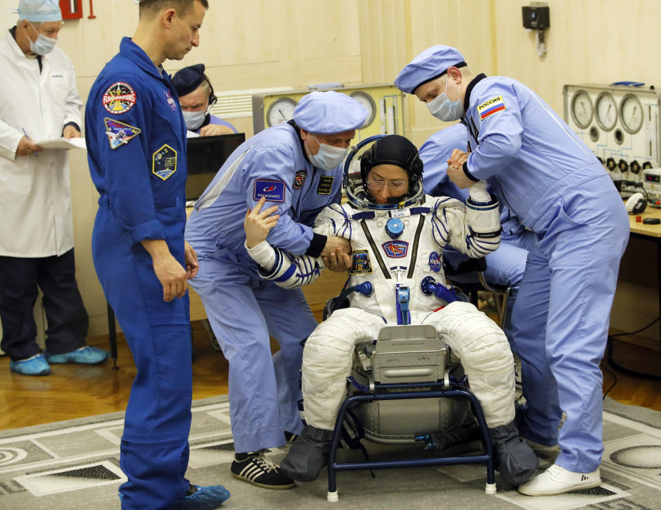 Russian Space Agency experts help U.S. astronaut Christina Hammock Koch, member of the main crew of the expedition to the International Space Station (ISS), to stand up after inspecting her space suit prior the launch of Soyuz MS-12 space ship at the Russian leased Baikonur cosmodrome, Kazakhstan, Thursday, March 14, 2019. (AP Photo/Dmitri Lovetsky, Pool)