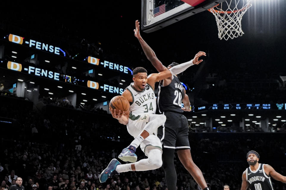 Milwaukee Bucks forward Giannis Antetokounmpo (34) looks to pass the ball while defended by Brooklyn Nets center Day'Ron Sharpe (20) during the first half of an NBA basketball game Wednesday, Dec. 27, 2023, in New York. (AP Photo/Peter K. Afriyie)