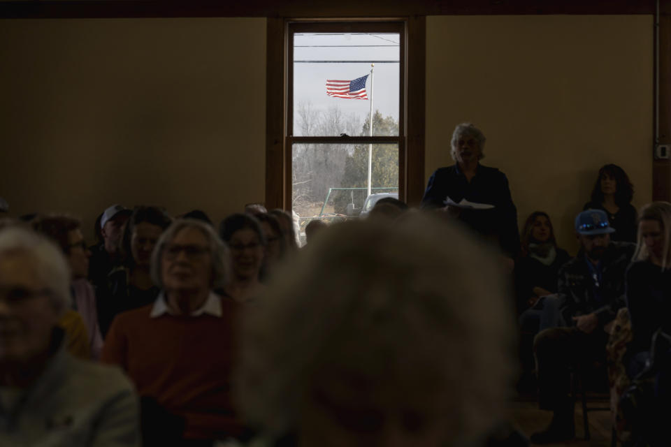 A U.S. flag flies in the wind outside the town hall as resident Shorty Towne speaks during the annual Town Meeting in Elmore, Vt., Tuesday, March 5, 2024. In Vermont, town meetings are traditionally held on the first Tuesday in March and in some towns, like Elmore, people sit down together afterwards for a potluck lunch. (AP Photo/David Goldman)