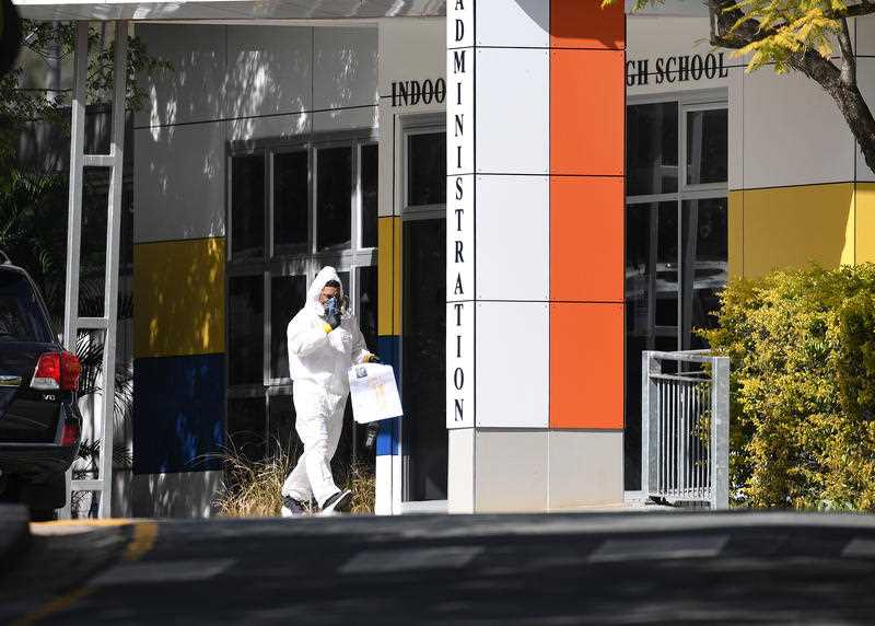 A cleaner in protective gear is seen at Indooroopilly State High School in Brisbane.