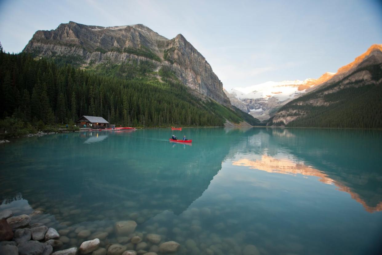 People canoe across the iconic Lake Louise in the Rocky Mountains in this file photo. Road work this summer may hamper access to the lake and other popular sites nearby. (Paul Zizka Photography/Banff & Lake Louise Tourism - image credit)