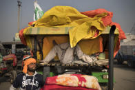 Balbir Singh rests on a makeshift bed placed on his tractor parked on a highway as part of a protest against new farm laws at the Delhi-Haryana state border, India, Tuesday, Dec. 1, 2020. Instead of cars, the normally busy highway on the outskirts of New Delhi that connects most northern Indian towns to the capital is filled with tens of thousands of protesting farmers, many wearing colorful turbans. Their convoy of trucks, trailers and tractors stretches for at least three kilometers (1.8 miles). Inside, they have hunkered down, supplied with enough food and fuel to last weeks. (AP Photo/Altaf Qadri)