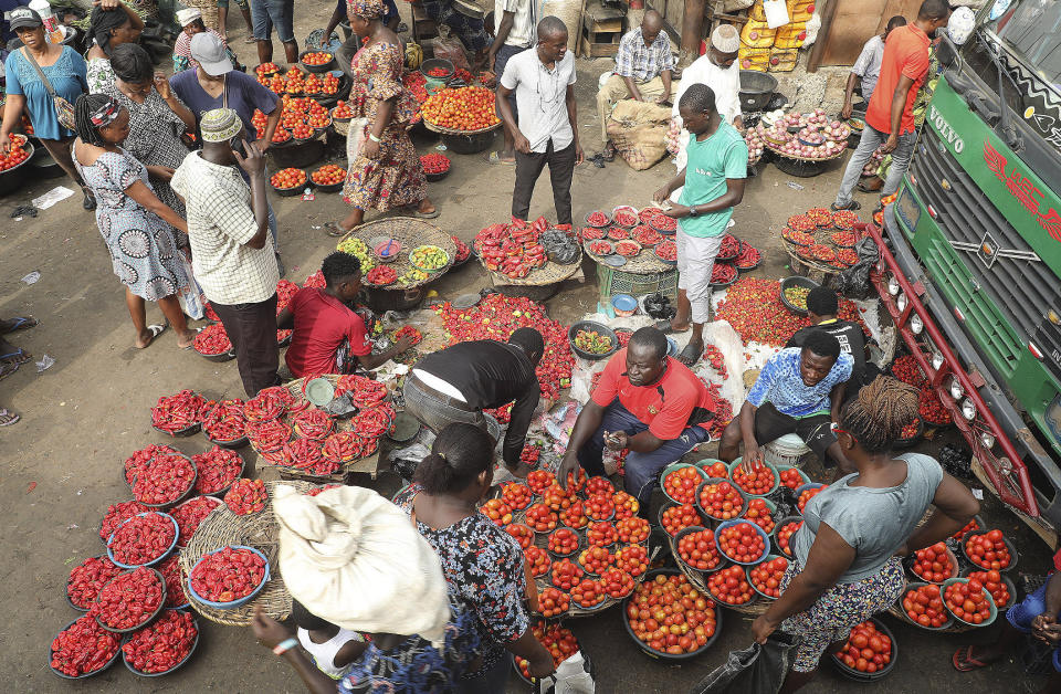 Pedestrians shop for tomatoes and other food items at the Mile 12 Market in Lagos, Nigeria, Friday, Feb. 16, 2024. Nigerians are facing one of the West African nation's worst economic crises in as many years triggered by a surging inflation rate which follows monetary policies that have dipped the local currency to an all-time low against the dollar, provoking anger and protests across the country. (AP Photo/Mansur Ibrahim)