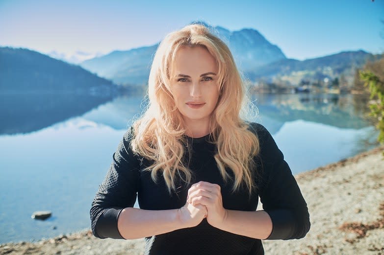 Rebel Wilson wearing a black top while posing in front of a lake in Austria