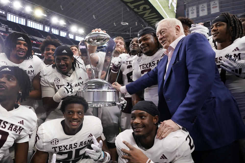 Dallas Cowboys owner Jerry Jones, right, presents the winner's trophy to Texas A&M players after an NCAA college football game against Jone's alma mater Arkansas, Saturday, Sept. 30, 2023, in Arlington, Texas. (AP Photo/LM Otero)