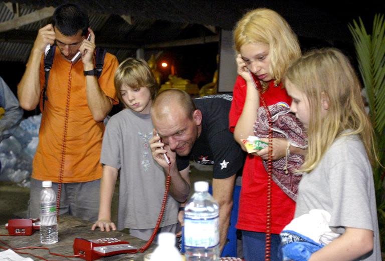 A day after the disaster, stranded tourists use phones provided for free at a Buddhist temple in Khao Lak, Thailand, so they can make international calls to give news to relatives and friends abroad