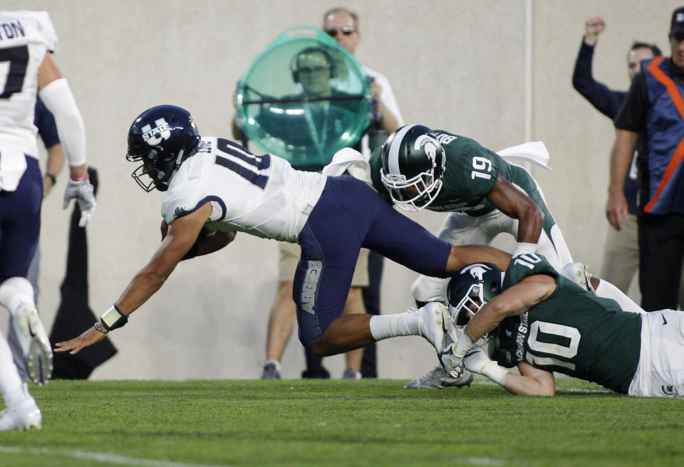 Utah State quarterback Jordan Love, left, is tripped by Michigan State's Matt Morrissey (10) and Josh Butler (19) during the second quarter of an NCAA college football game, Friday, Aug. 31, 2018, in East Lansing, Mich. (AP Photo/Al Goldis)