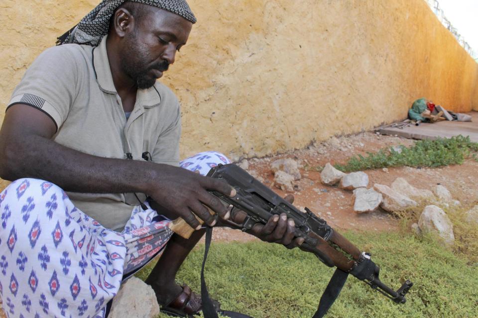 In this photo taken Monday, Sept. 17, 2012, Somali pirate Mohamed Jama maintains the gun he has not used for months, in the once-bustling pirate town of Galkayo, Somalia. The empty whisky bottles and overturned, sand-filled skiffs that litter this shoreline are signs that the heyday of Somali piracy may be over - most of the prostitutes are gone, the luxury cars repossessed, and pirates talk more about catching lobsters than seizing cargo ships. (AP Photo/Farah Abdi Warsameh)