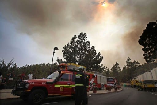 Firemen stand next to their truck in the town of Vilaflor on the Spanish Canary Island of Tenerife. Emergency services "are evacuating residents from Vilaflor due to the advance of the fire from the east," the regional government said